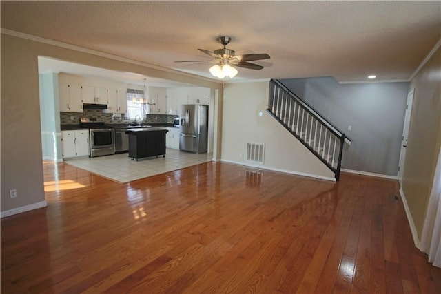 unfurnished living room with light hardwood / wood-style floors, ceiling fan, a textured ceiling, ornamental molding, and sink