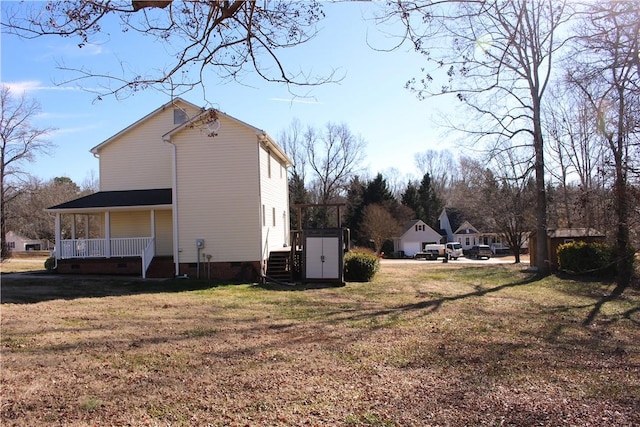 view of side of home with a shed, a yard, and covered porch