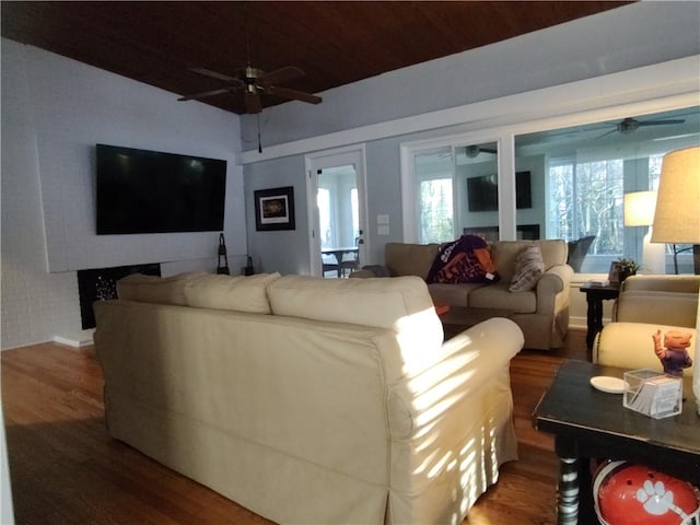 living room with ceiling fan, brick wall, and hardwood / wood-style floors