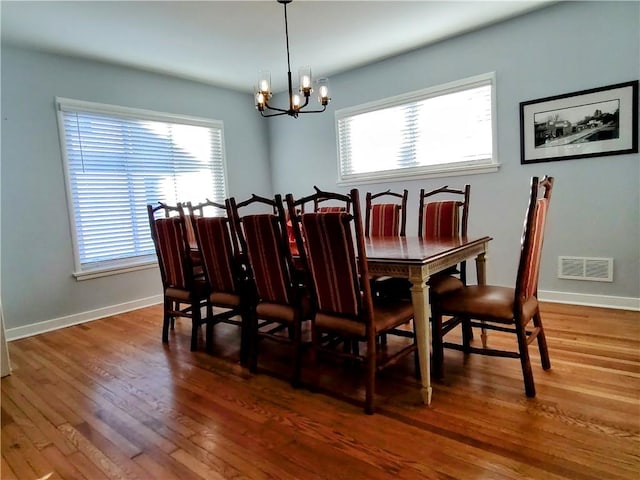 dining space featuring wood-type flooring and a chandelier