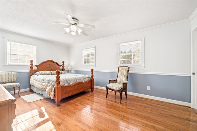 bedroom with a textured ceiling, ceiling fan, ornamental molding, and light hardwood / wood-style flooring