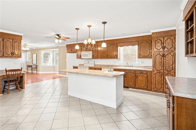 kitchen with ceiling fan with notable chandelier, white appliances, an island with sink, hanging light fixtures, and crown molding