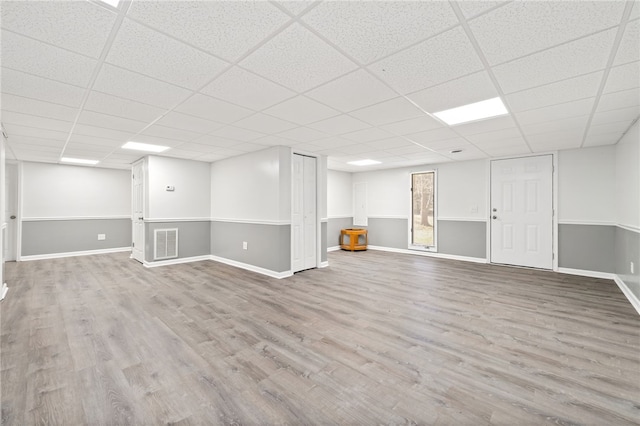 basement with light hardwood / wood-style floors and a paneled ceiling