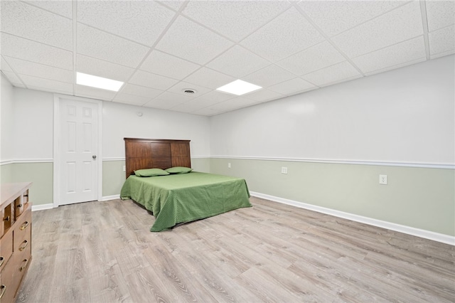 unfurnished bedroom with a paneled ceiling and light wood-type flooring