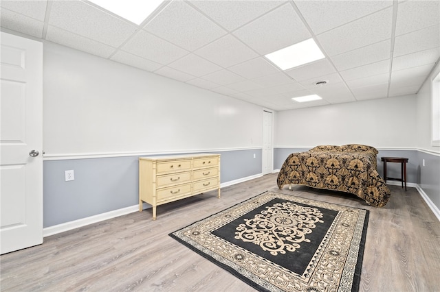 bedroom with hardwood / wood-style floors and a paneled ceiling