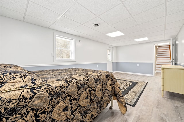 bedroom featuring a drop ceiling and light hardwood / wood-style flooring