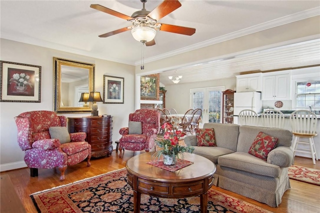 living room with ceiling fan with notable chandelier, hardwood / wood-style floors, and crown molding