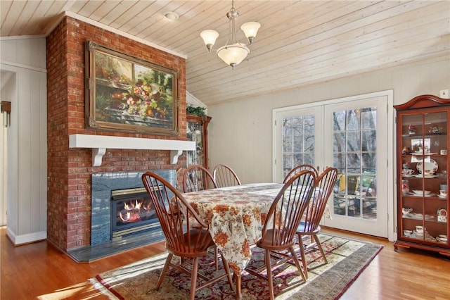 dining space with an inviting chandelier, wood ceiling, a fireplace, and wood-type flooring