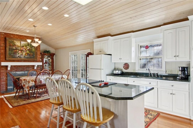 kitchen featuring white cabinetry, sink, light wood-type flooring, white refrigerator, and a center island