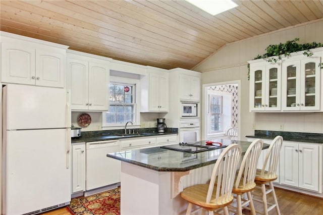 kitchen with a center island, white appliances, vaulted ceiling, white cabinets, and sink