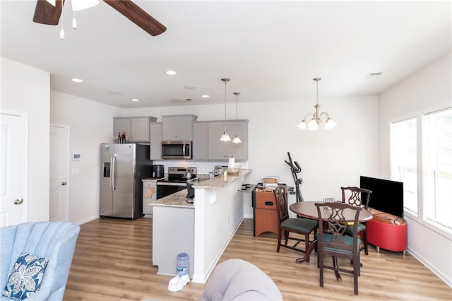 kitchen featuring stainless steel appliances, tasteful backsplash, hanging light fixtures, gray cabinets, and kitchen peninsula