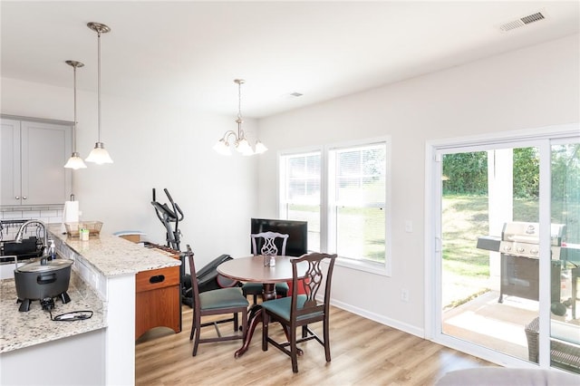 dining space featuring a wealth of natural light, light hardwood / wood-style flooring, and a notable chandelier