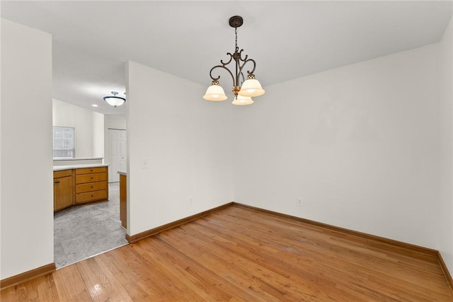 unfurnished dining area featuring light hardwood / wood-style flooring and an inviting chandelier