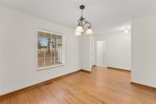 unfurnished room with a chandelier and hardwood / wood-style floors