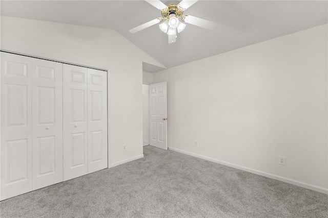 unfurnished bedroom with vaulted ceiling, ceiling fan, a closet, and light colored carpet