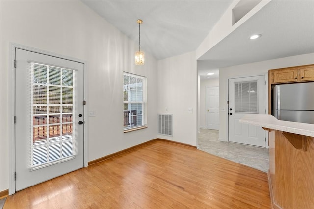 interior space featuring light wood-type flooring, vaulted ceiling, and a chandelier