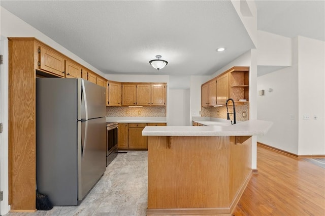 kitchen featuring tasteful backsplash, light wood-type flooring, appliances with stainless steel finishes, and a breakfast bar area