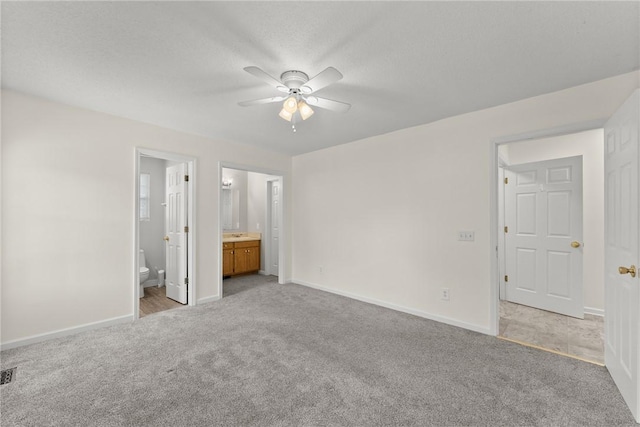 unfurnished bedroom featuring light carpet, ceiling fan, and ensuite bathroom