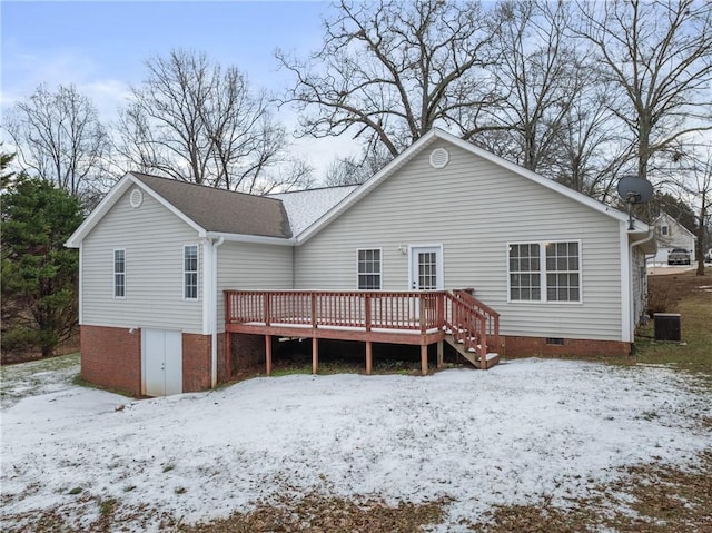 snow covered back of property with central AC unit and a wooden deck