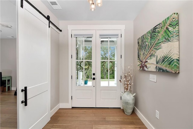 doorway featuring a barn door, french doors, and light hardwood / wood-style flooring