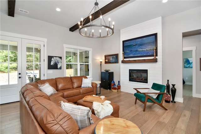 living room featuring a notable chandelier, light hardwood / wood-style floors, a large fireplace, beamed ceiling, and french doors