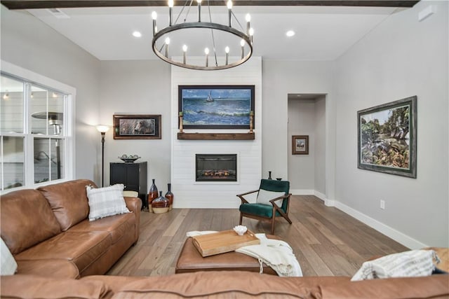 living room featuring a fireplace, an inviting chandelier, and light hardwood / wood-style floors