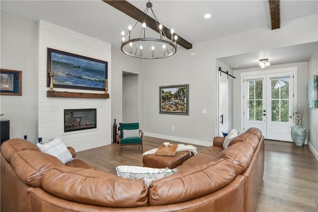 living room with a barn door, hardwood / wood-style flooring, a large fireplace, french doors, and beamed ceiling