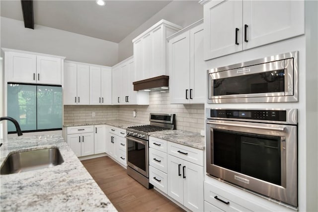 kitchen featuring beam ceiling, white cabinets, light stone countertops, and appliances with stainless steel finishes