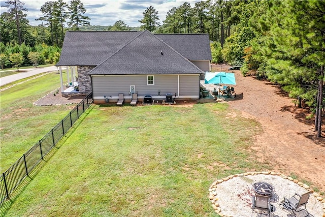 back of house featuring an outdoor fire pit and a lawn