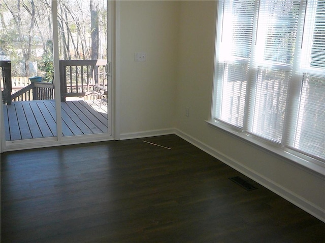 unfurnished dining area with dark wood-style floors, visible vents, and baseboards