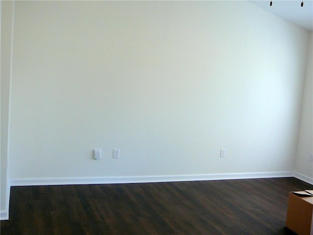 empty room featuring baseboards and dark wood-style flooring