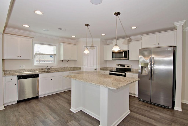 kitchen featuring decorative light fixtures, white cabinets, appliances with stainless steel finishes, and a kitchen island