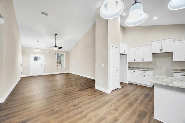 kitchen with ceiling fan, white cabinetry, hardwood / wood-style flooring, high vaulted ceiling, and light stone counters