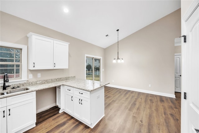 kitchen featuring lofted ceiling, hardwood / wood-style floors, kitchen peninsula, sink, and white cabinetry