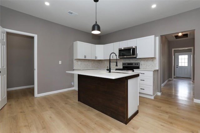 kitchen featuring stainless steel appliances, decorative backsplash, a kitchen island with sink, hanging light fixtures, and white cabinets