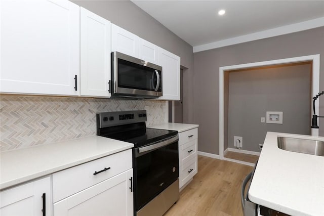 kitchen featuring backsplash, sink, light wood-type flooring, stainless steel appliances, and white cabinets