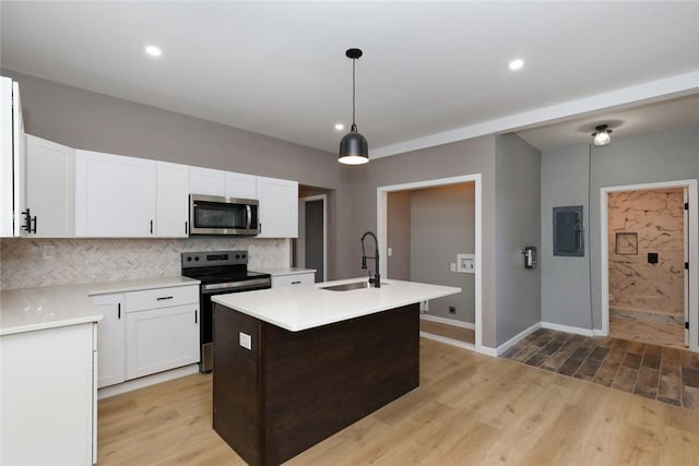 kitchen with appliances with stainless steel finishes, sink, white cabinetry, and a center island with sink