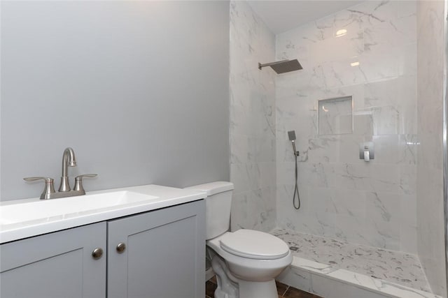 bathroom with toilet, vanity, and a tile shower