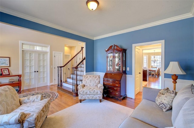 living room with crown molding, french doors, and light wood-type flooring