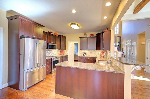 kitchen with tasteful backsplash, kitchen peninsula, a kitchen bar, sink, and stainless steel appliances