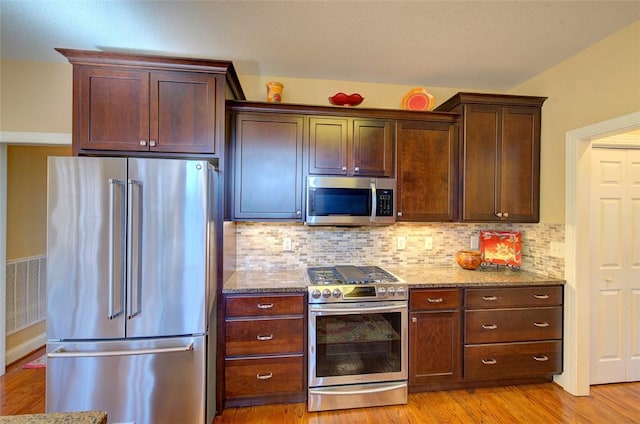 kitchen with stainless steel appliances, light hardwood / wood-style floors, backsplash, light stone counters, and dark brown cabinets