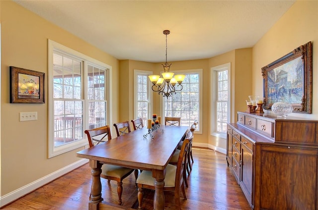 dining area with a wealth of natural light, hardwood / wood-style flooring, and a notable chandelier