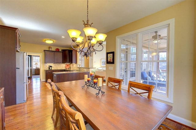 dining area featuring ceiling fan with notable chandelier, light hardwood / wood-style floors, and sink