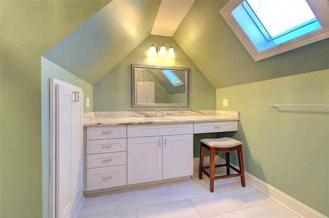 bathroom with vanity and vaulted ceiling with skylight