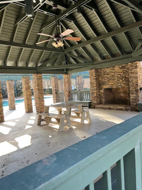 view of patio featuring ceiling fan, a gazebo, and an outdoor stone fireplace