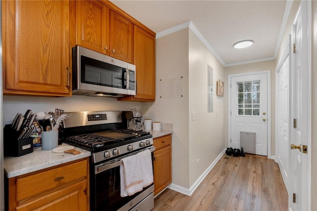 kitchen featuring light hardwood / wood-style floors, light stone countertops, appliances with stainless steel finishes, and ornamental molding