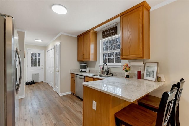 kitchen featuring kitchen peninsula, stainless steel appliances, light wood-type flooring, crown molding, and sink