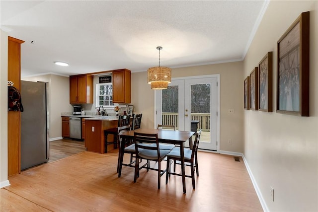 dining area with crown molding, light hardwood / wood-style floors, french doors, and sink