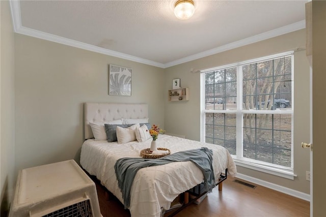 bedroom featuring crown molding, hardwood / wood-style flooring, and multiple windows