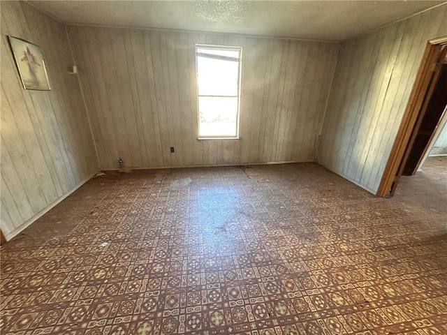 spare room with a textured ceiling and wood walls